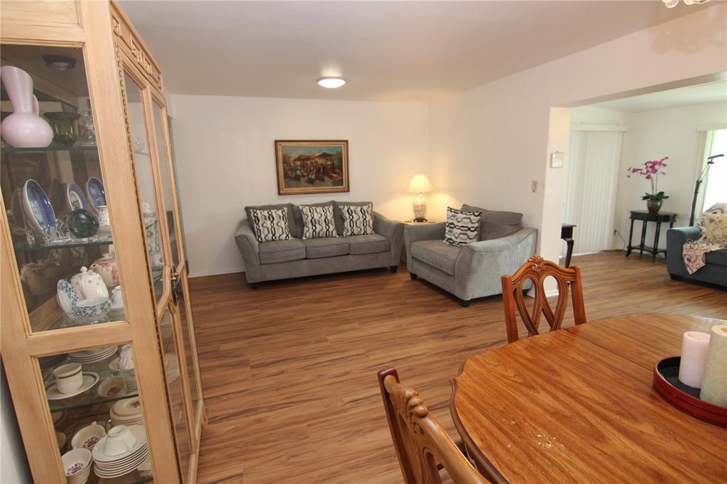 A living room and dining area with wood-look flooring, a china cabinet, and gray furniture — 810 OAKMONT AVENUE, SUN CITY CENTER, FL