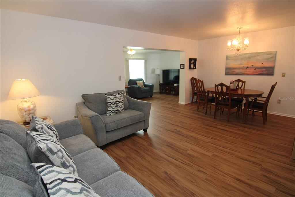 A living room and dining area with wood-look flooring and neutral walls — 810 OAKMONT AVENUE, SUN CITY CENTER, FL