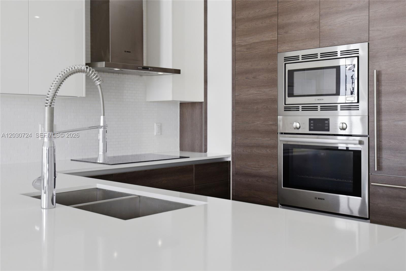 A modern kitchen features white countertops, dark wood cabinetry, and stainless steel Bosch appliances — 301 Altara Ave, Coral Gables FL 33146, CORAL GABLES, FL