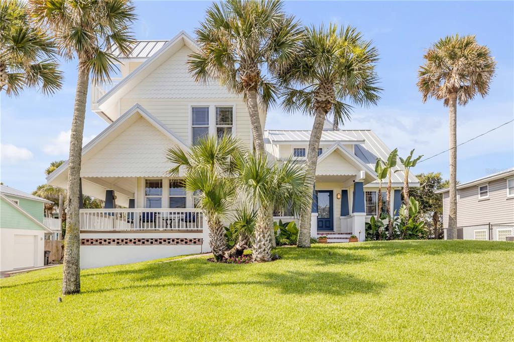 A two-story house with light siding, a metal roof, and palm trees in the front yard — 315 DUE EAST STREET, NEW SMYRNA BEACH, FL