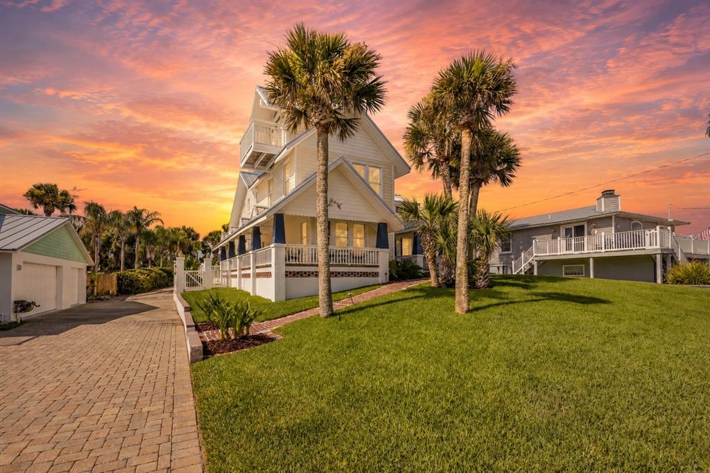 A multi-story coastal home with a wraparound porch and palm trees under a sunset sky — 315 DUE EAST STREET, NEW SMYRNA BEACH, FL