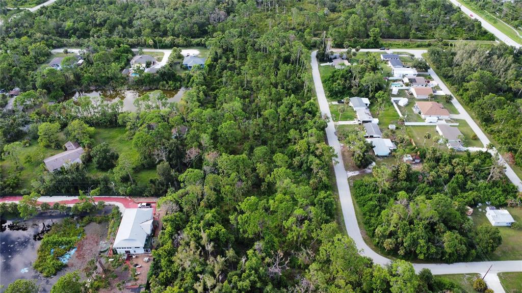 An aerial view shows a residential neighborhood with houses, a pond, and dense wooded areas — 2 BERTREND STREET, ENGLEWOOD, FL