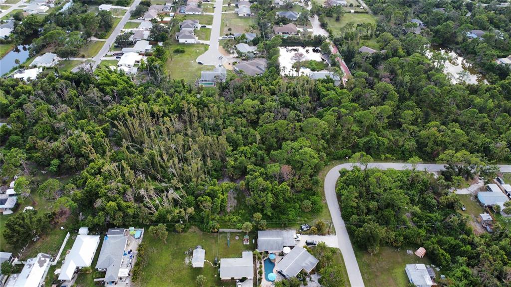 An aerial view shows a residential neighborhood with houses surrounded by dense wooded areas — 2 BERTREND STREET, ENGLEWOOD, FL