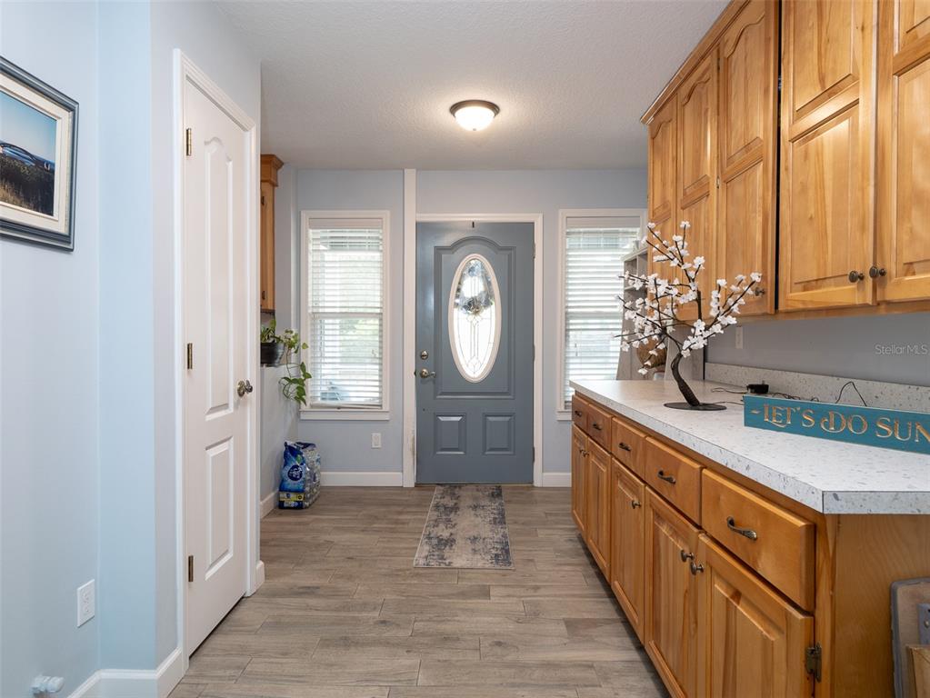 An entryway features light blue walls, wood-look tile flooring, and light wood cabinetry — 5119 HESKETT LANE, KEYSTONE HEIGHTS, FL