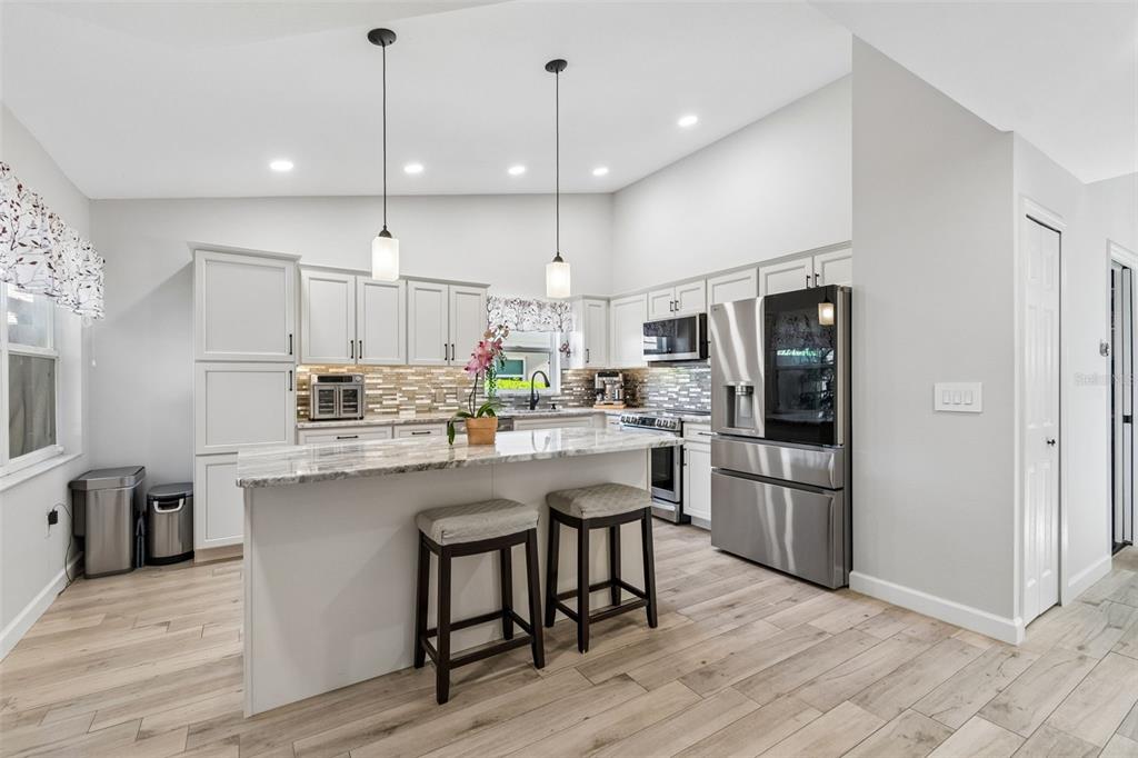 A white wet bar features glass-front cabinets, a wine cooler, and shiplap wall paneling — 5613 MONTE ROSSO ROAD, SARASOTA, FL