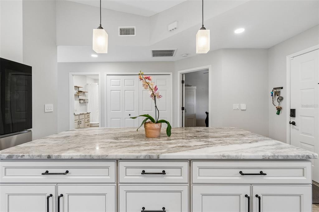 A kitchen island with a marble countertop sits in front of white cabinets and doorways — 5613 MONTE ROSSO ROAD, SARASOTA, FL
