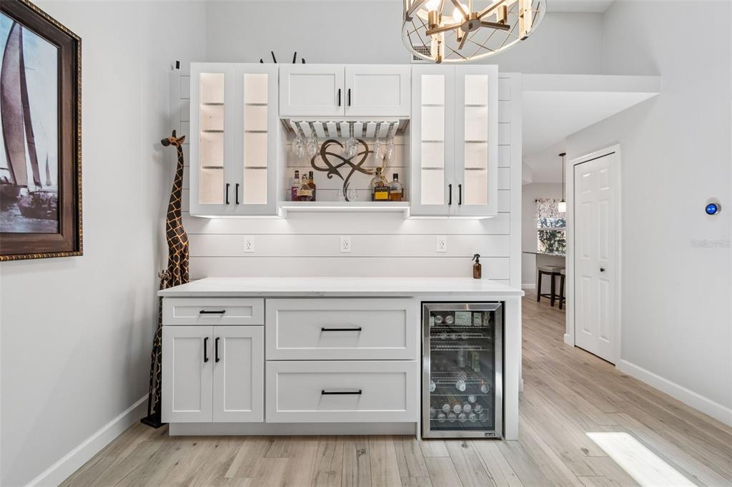 A modern kitchen with a stone island, stainless steel appliances, and light wood-look flooring — 5613 MONTE ROSSO ROAD, SARASOTA, FL