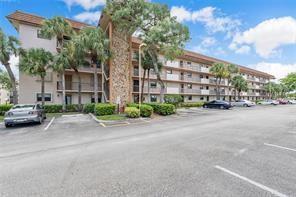 A multi-story apartment building with a stone facade and palm trees in the parking lot — 4930 E Sabal Palm Boulevard # 402, Tamarac FL 33319, TAMARAC, FL