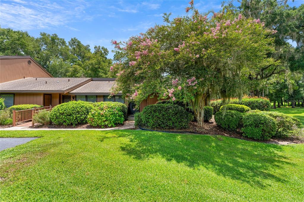 A brown house with a large flowering tree and manicured bushes in the front yard — 19660 SW 83RD PLACE ROAD UNIT C13, DUNNELLON, FL
