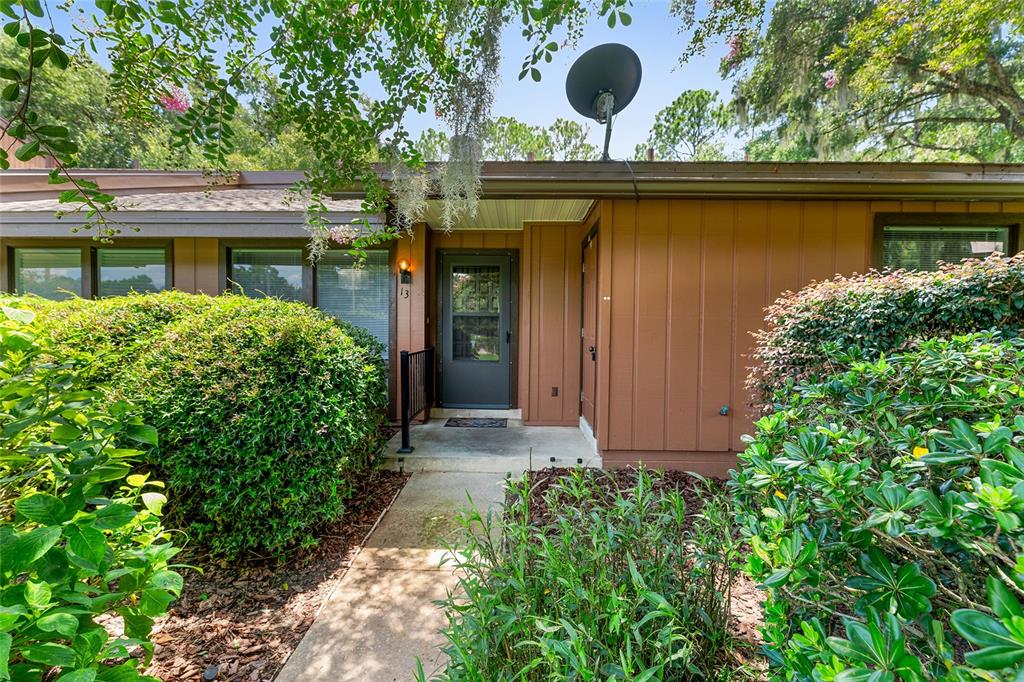 The exterior of a brown house features a front door, a walkway, and landscaping — 19660 SW 83RD PLACE ROAD UNIT C13, DUNNELLON, FL