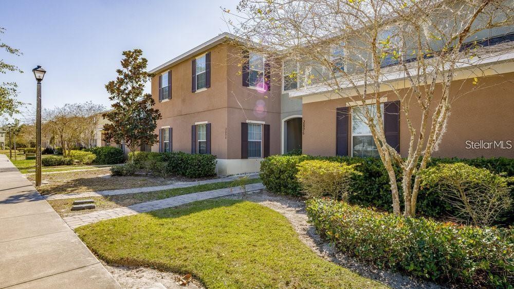 The exterior of a two-story townhouse features a stone walkway leading to two front doors — 2896 TANZANITE TERRACE, KISSIMMEE, FL