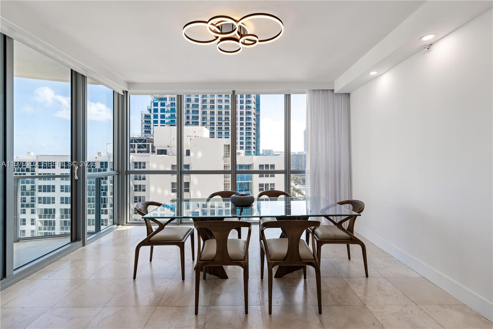 A dining room features a glass table, six wooden chairs, and floor-to-ceiling windows — 3101 S Ocean Dr # 1504, Hollywood FL 33019, HOLLYWOOD, FL