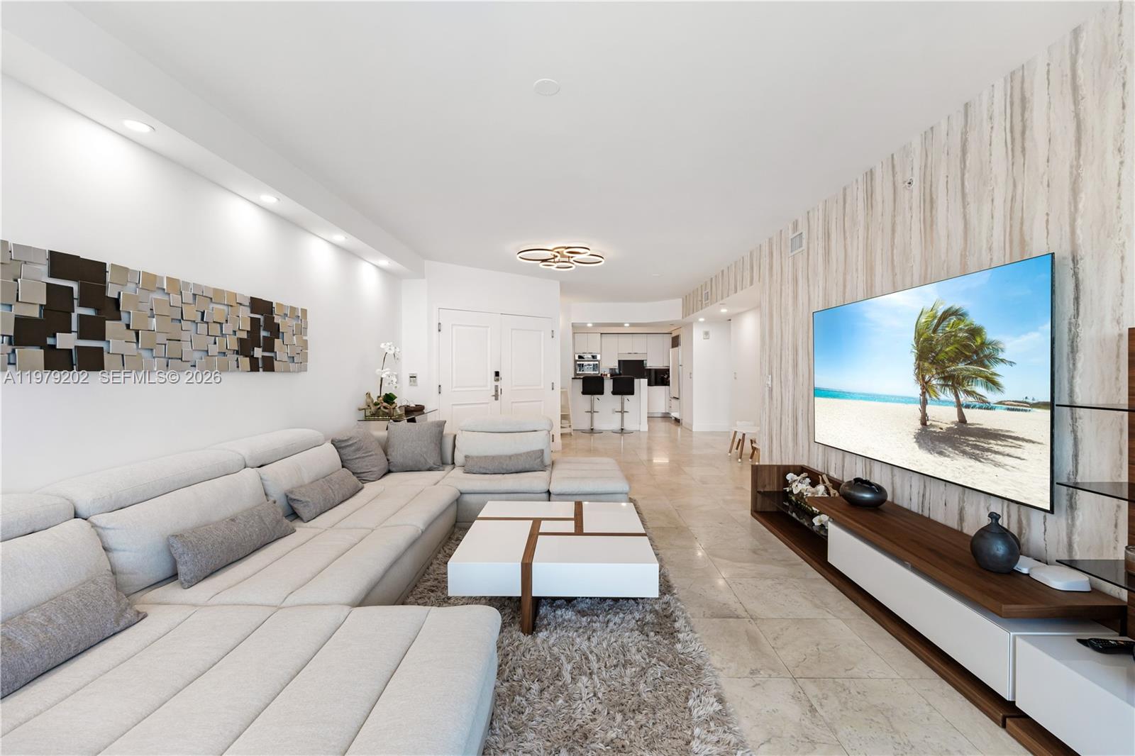 A modern living room features a large sectional sofa, a white coffee table, and a television — 3101 S Ocean Dr # 1504, Hollywood FL 33019, HOLLYWOOD, FL