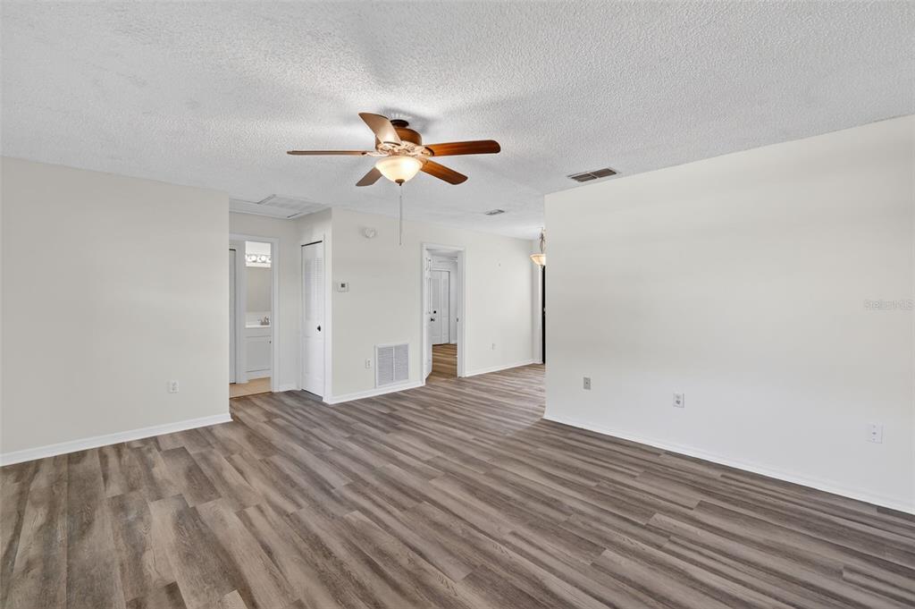 An empty room with light-colored walls, a ceiling fan, and wood-look vinyl flooring — 12520 ORANGEWOOD COURT, TAVARES, FL