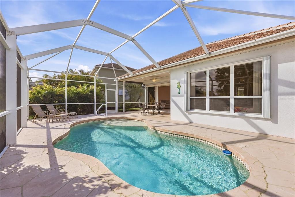 A screened-in patio features a kidney-shaped swimming pool and a paved deck — 3239 OSPREY LN, PORT CHARLOTTE, FL
