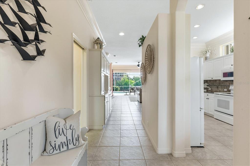 A hallway with tile floors leads from a foyer toward a kitchen and outdoor patio — 3239 OSPREY LN, PORT CHARLOTTE, FL