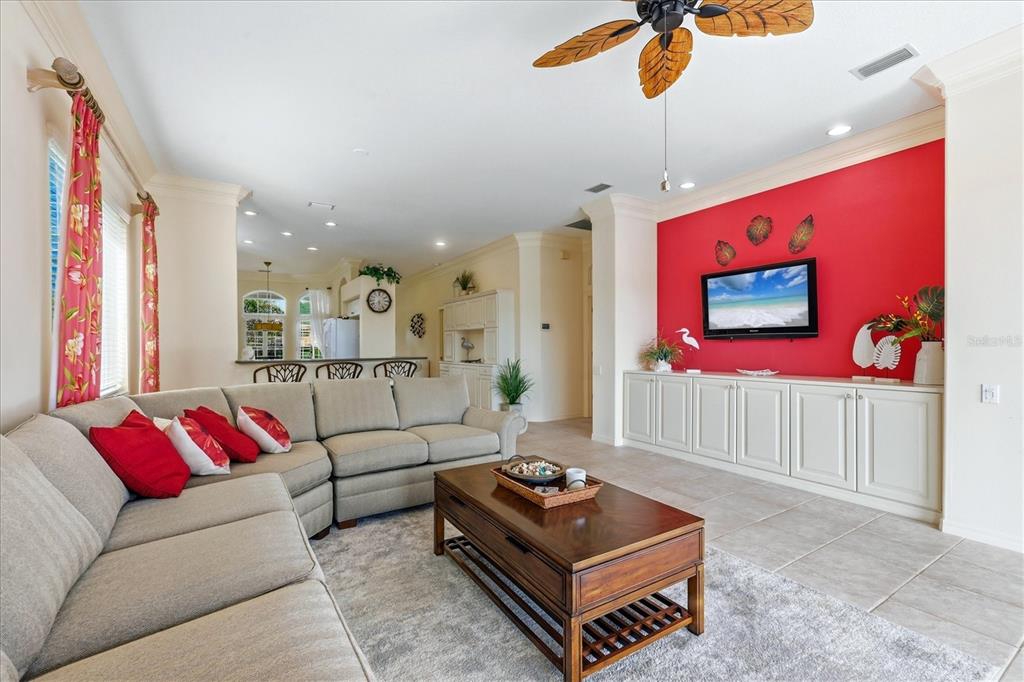 A living room features a large sectional sofa, a coffee table, and a red accent wall — 3239 OSPREY LN, PORT CHARLOTTE, FL