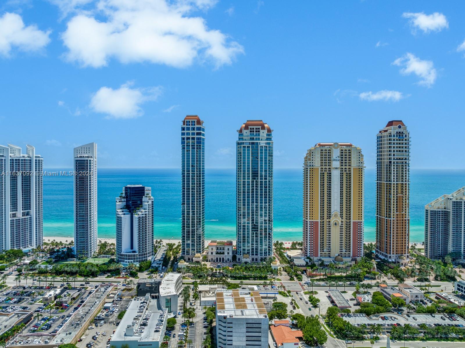 An aerial view shows several tall residential skyscrapers along a sandy beach and ocean — 17901 Collins, Sunny Isles Beach FL 33160, SUNNY ISLES BEACH, FL