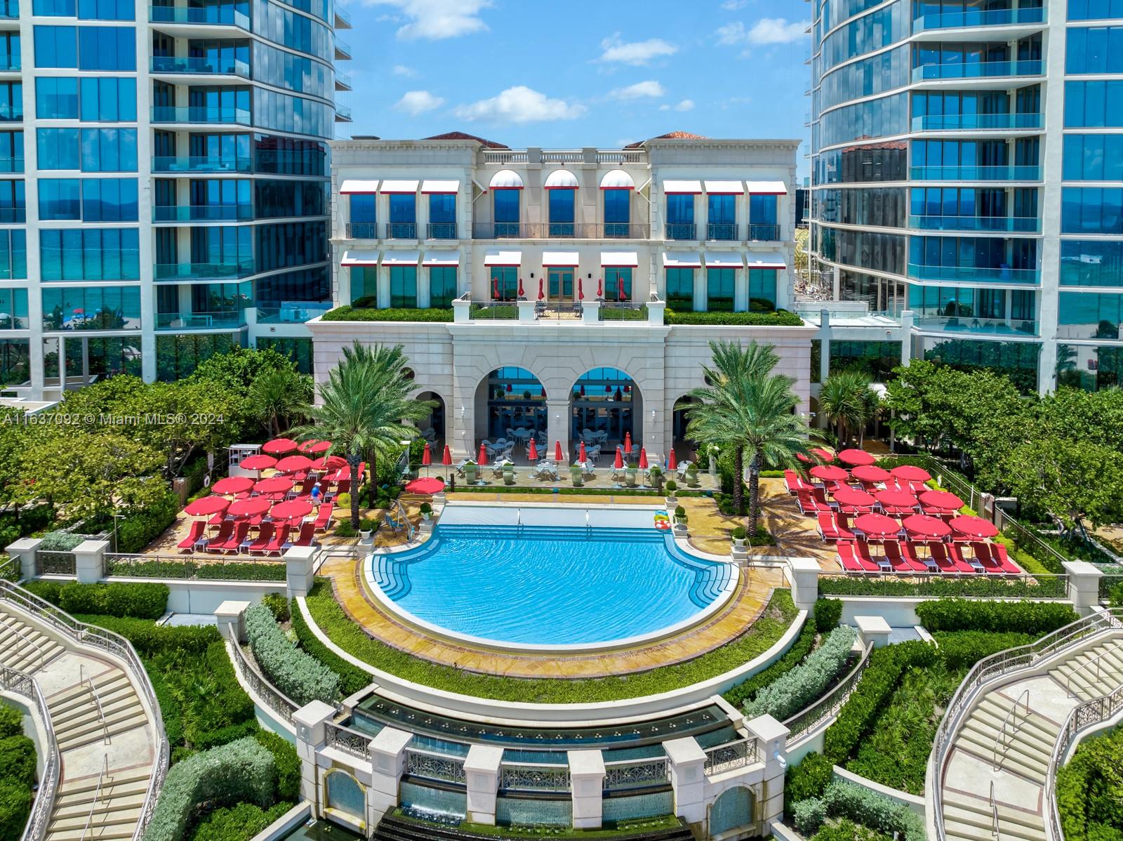 An aerial view of a swimming pool surrounded by lounge chairs between two glass towers — 17901 Collins, Sunny Isles Beach FL 33160, SUNNY ISLES BEACH, FL
