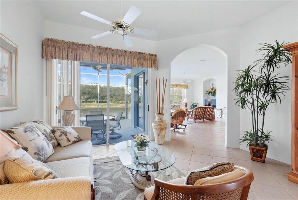 A bright living room features tile flooring, a large sliding glass door, and decorative accents — 3175 VILLAGE LANE, PORT CHARLOTTE, FL