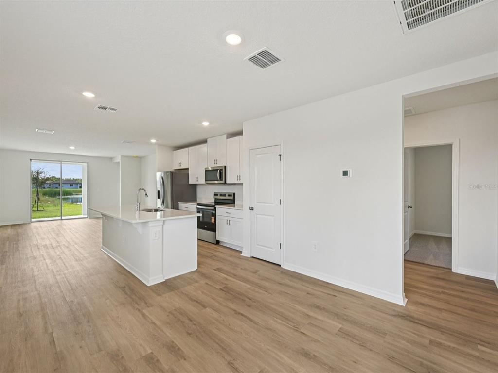 A bright kitchen with white cabinets, a central island, and wood-look flooring — 13617 SHELLMORE AVENUE, PALMETTO, FL
