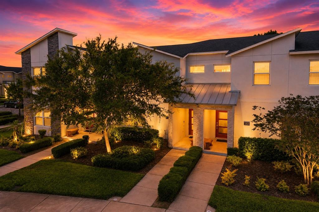 A two-story townhouse exterior with a metal-roofed entryway and landscaped front yard at sunset — 374 OCEAN COURSE AVENUE, DAVENPORT, FL