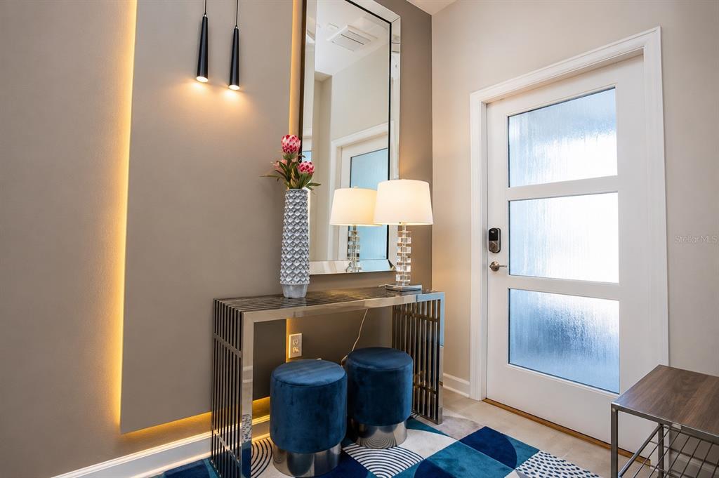 An entryway features a metal console table, blue velvet stools, a mirror, and accent lighting — 374 OCEAN COURSE AVENUE, DAVENPORT, FL