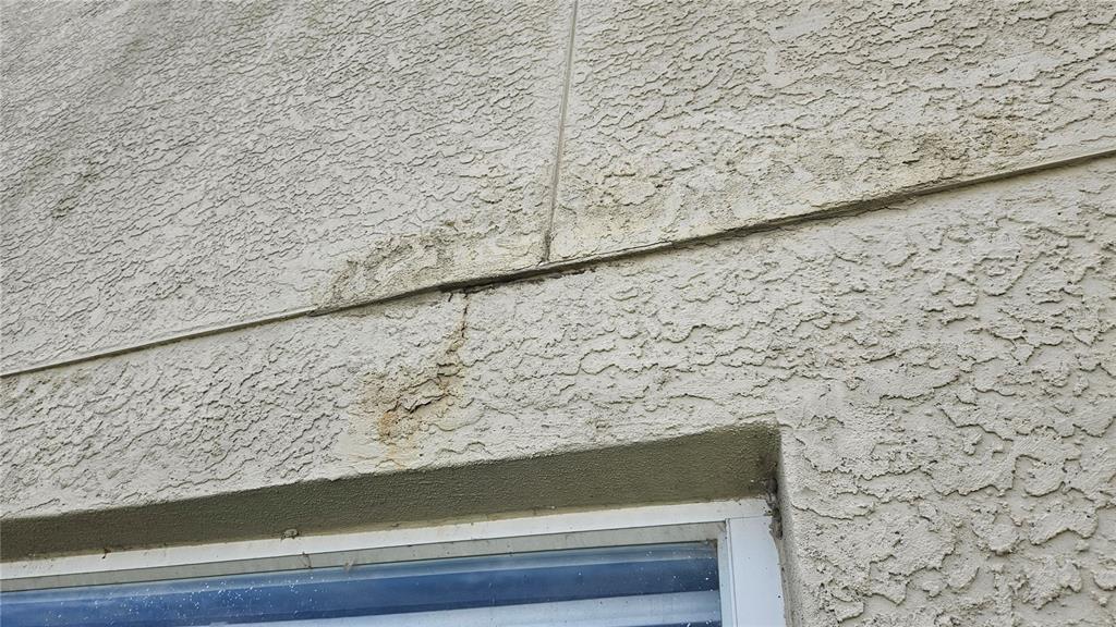 Exterior view of a stucco wall showing cracks and water damage above a window — 6836 ARAMON COURT, WESLEY CHAPEL, FL
