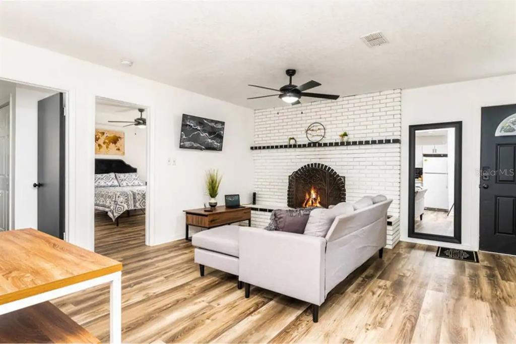 A living room features a white brick fireplace, wood-look flooring, and a gray sectional sofa — 2301 CARLTON DRIVE, ORLANDO, FL