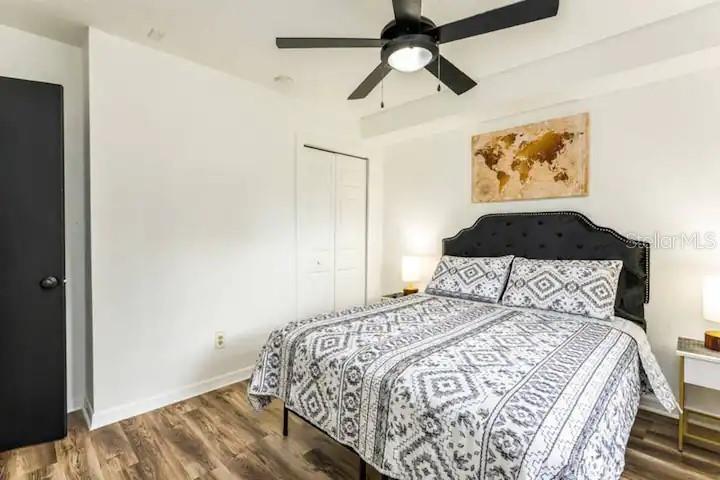 A bedroom features a bed with a patterned comforter, a ceiling fan, and wood flooring — 2301 CARLTON DRIVE, ORLANDO, FL