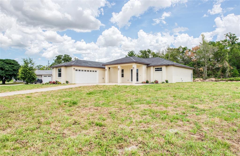 A single-story beige house with a two-car garage and a covered front porch — 12027 VILLA ROAD, SPRING HILL, FL