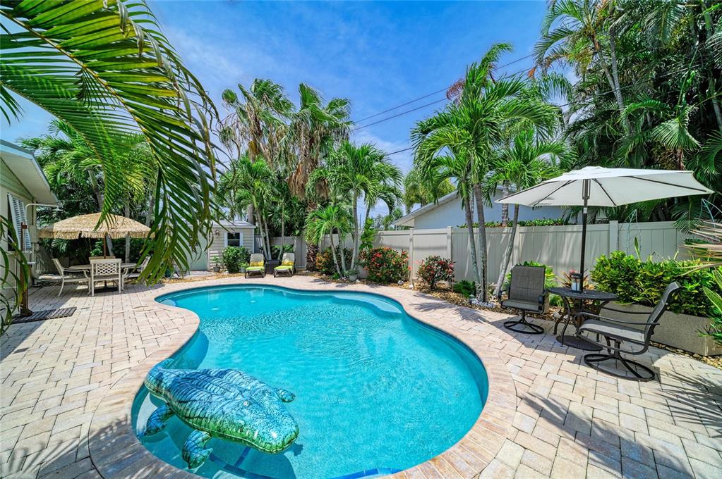 A backyard swimming pool with a patio, palm trees, and an umbrella-covered seating area — 2711 AVENUE C, HOLMES BEACH, FL