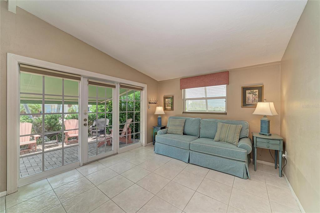 A sunroom features a blue sofa, two side tables with lamps, and sliding glass patio doors — 2711 AVENUE C, HOLMES BEACH, FL