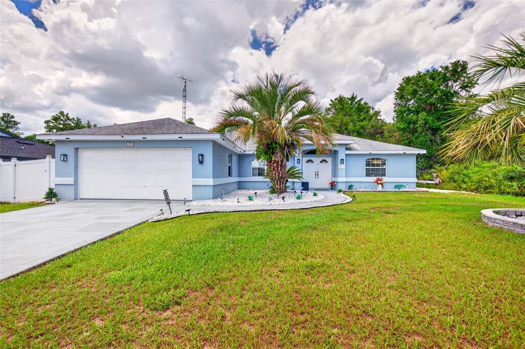A light blue single-story house features a two-car garage, a palm tree, and a lawn — 15474 SW 28TH AVENUE RD, OCALA, FL