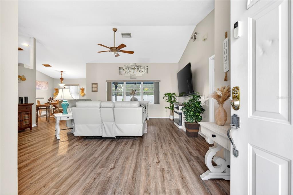 A bright living room features wood-look flooring, a white sofa, and a wall-mounted television — 15474 SW 28TH AVENUE RD, OCALA, FL