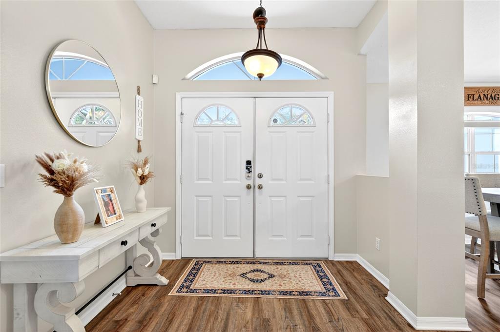 A bright entryway features a white double door, a console table, and a round mirror — 15474 SW 28TH AVENUE RD, OCALA, FL