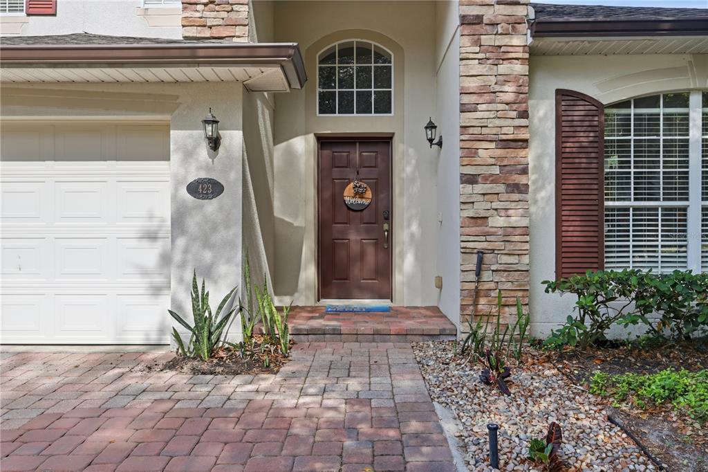 The exterior of a house features a brick walkway, a brown front door, and stone accents — 423 VICTORIA HILLS DRIVE, DELAND, FL