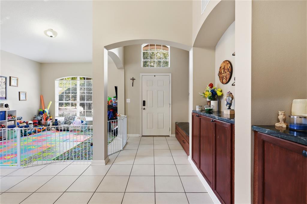 An entryway with tile flooring leads to a front door and a gated play area — 423 VICTORIA HILLS DRIVE, DELAND, FL
