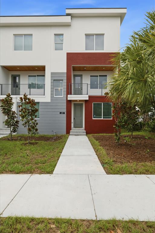 The exterior of a modern two-story townhouse features a red brick facade and a balcony — 2138 W NASSAU STREET UNIT 3, TAMPA, FL