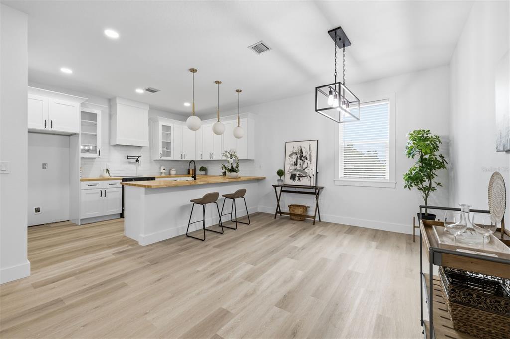 A bright kitchen features white cabinetry, a wood countertop island with stools, and light flooring — 2138 W NASSAU STREET UNIT 3, TAMPA, FL