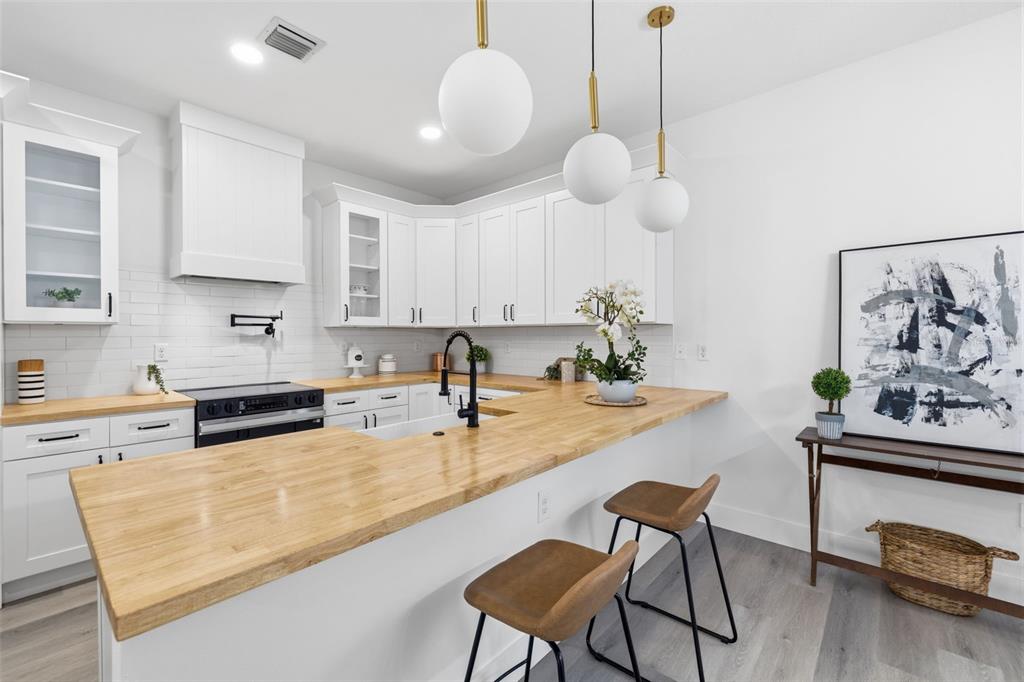 A kitchen features white cabinets, a wood countertop, and three globe pendant lights — 2138 W NASSAU STREET UNIT 3, TAMPA, FL