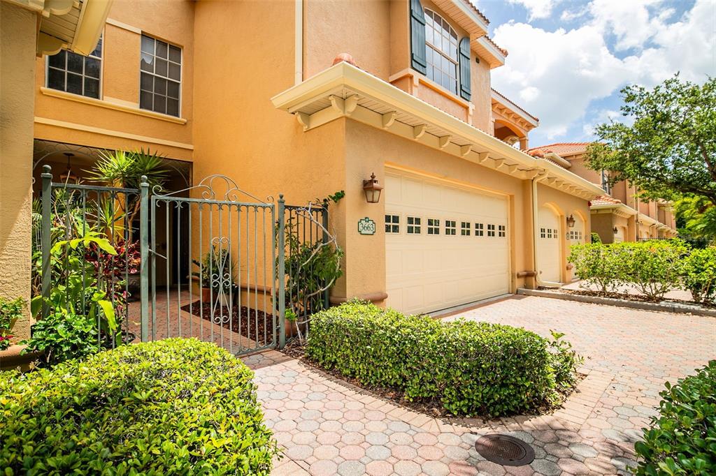 A two-story townhouse with a beige stucco exterior, a two-car garage, and green shutters — 3663 SQUARE WEST LANE UNIT 12, SARASOTA, FL