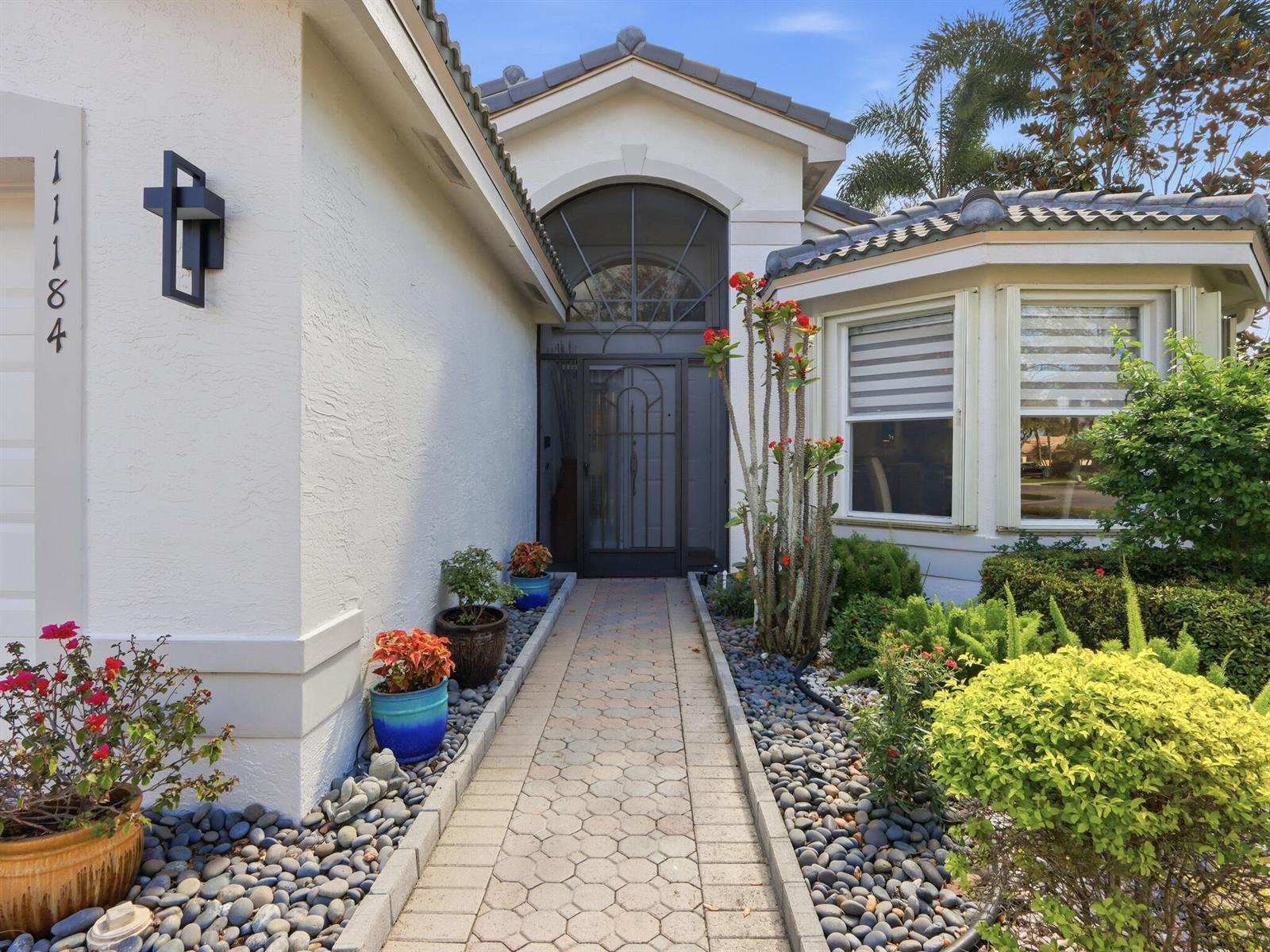 A paved walkway leads to the front entrance of a house with a white exterior — 11184 Ihilani Way, Boynton Beach FL 33437, BOYNTON BEACH, FL