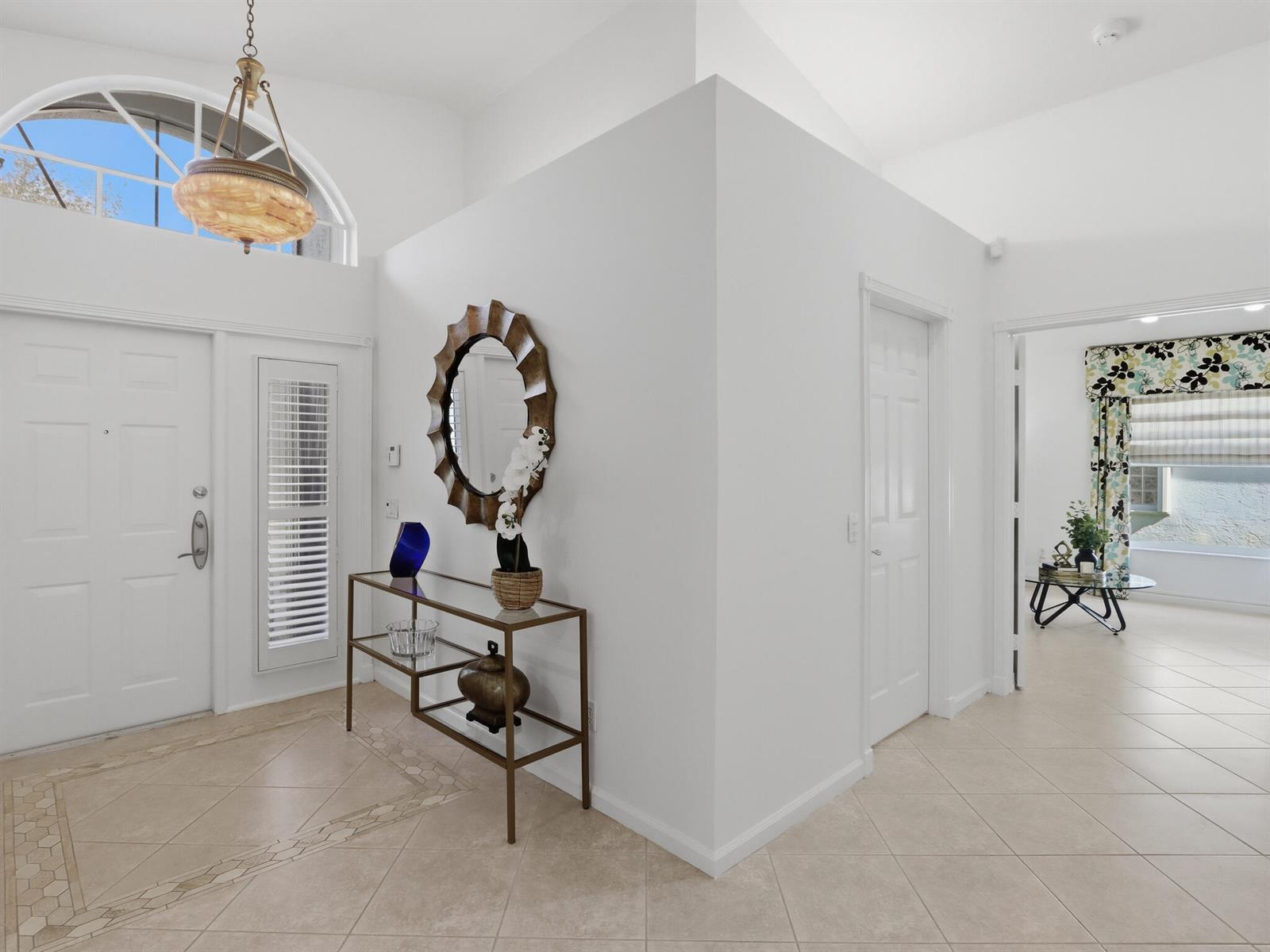 A bright entryway features tile flooring, a glass console table, a mirror, and arched windows — 11184 Ihilani Way, Boynton Beach FL 33437, BOYNTON BEACH, FL