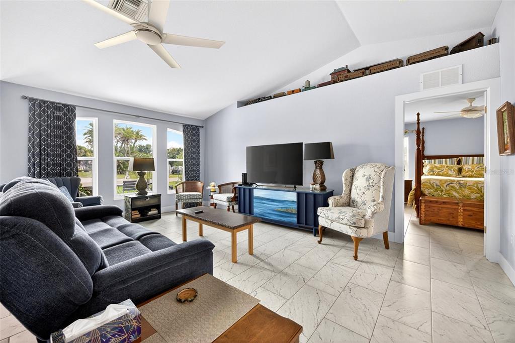 A living room features a blue sofa, a television on a console, and tiled floors — 25652 AYSEN DRIVE, PUNTA GORDA, FL