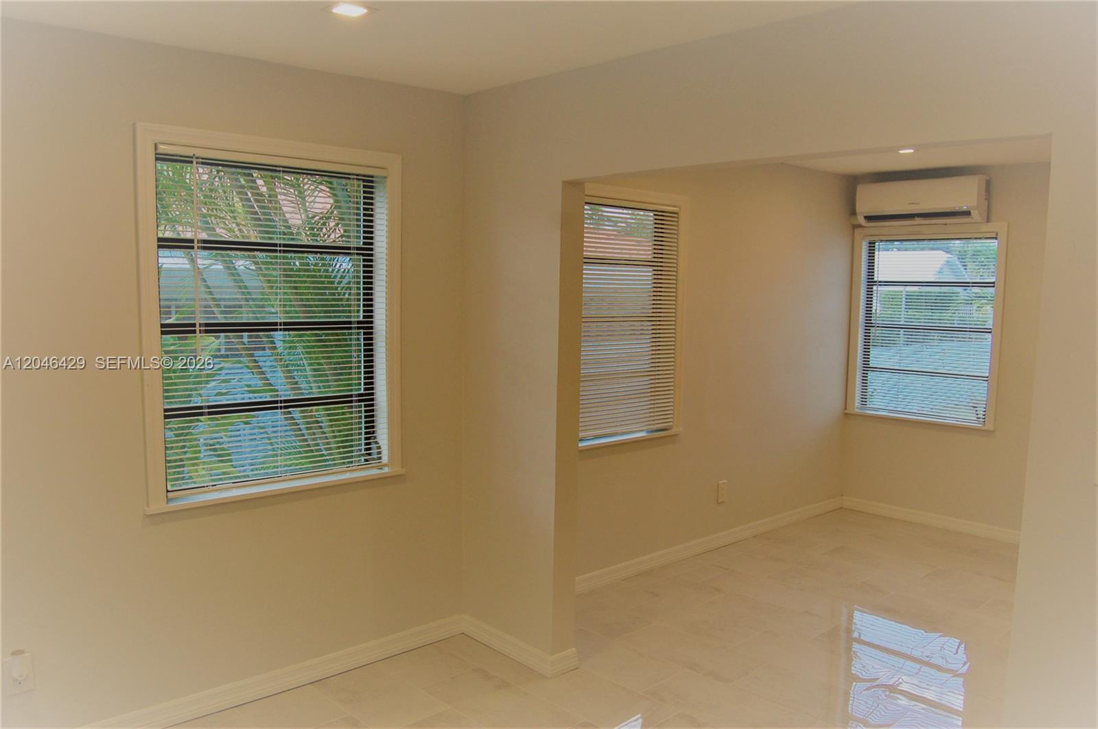 An interior room features light-colored tile flooring, neutral walls, and three windows with blinds — MIAMI, FL