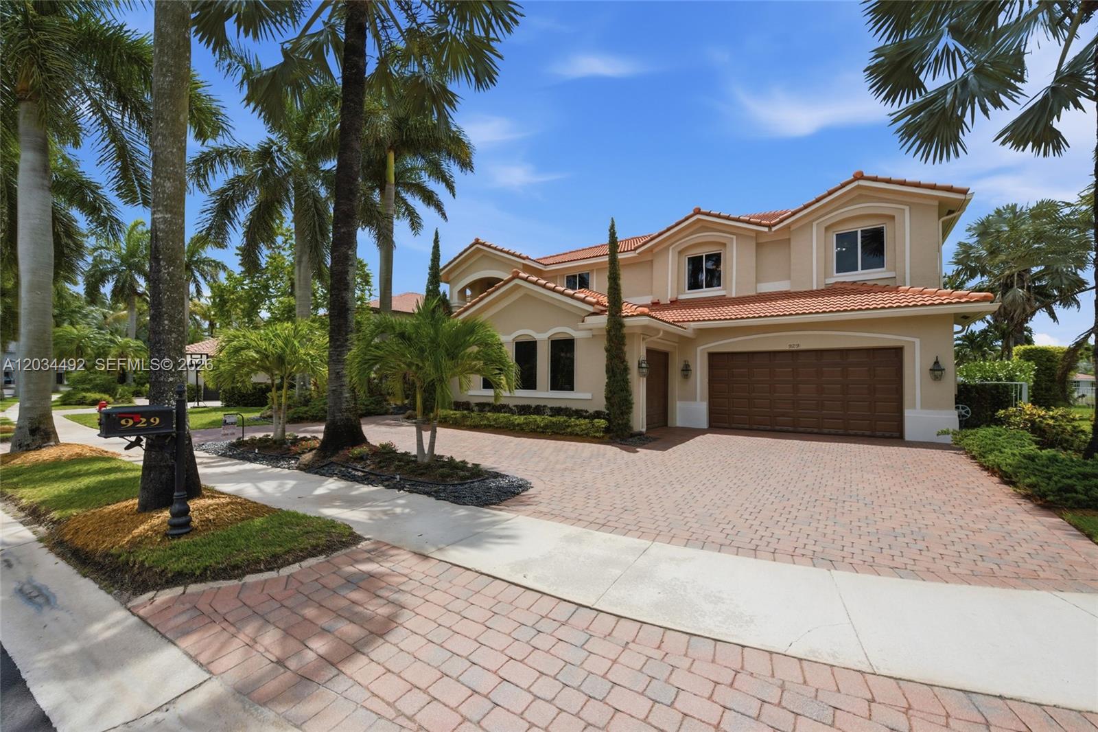 A two-story suburban house with a tiled roof, beige stucco walls, and a brick driveway — 929 Gulfstream Ct, Weston FL 33327, WESTON, FL