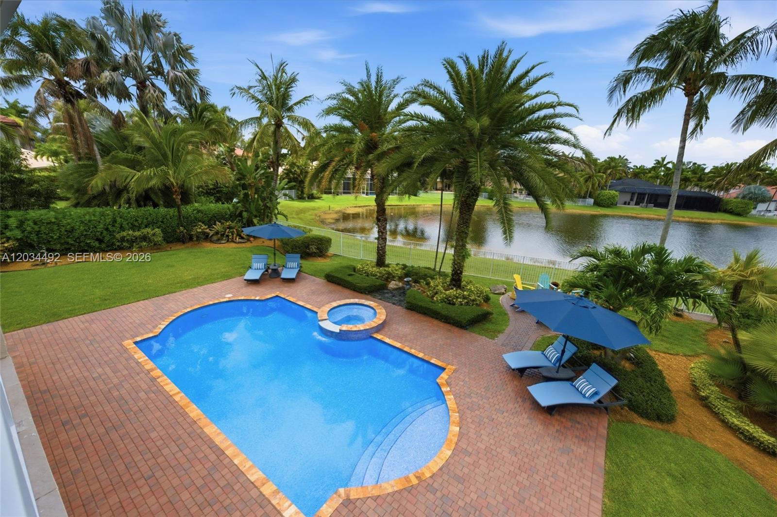 An aerial view of a backyard featuring a swimming pool, spa, patio, and lake view — 929 Gulfstream Ct, Weston FL 33327, WESTON, FL