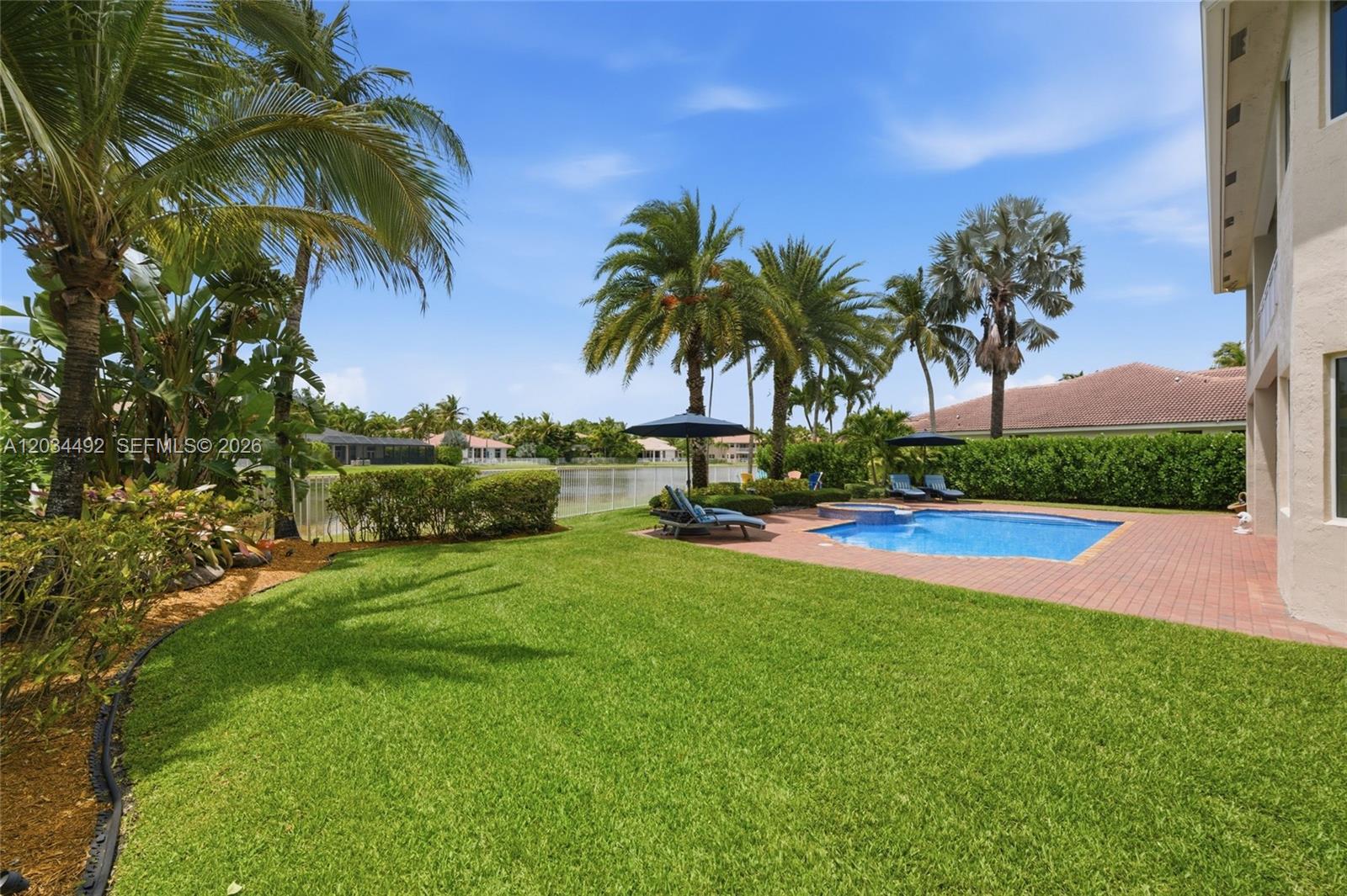 A backyard features a swimming pool, patio, palm trees, and a view of a lake — 929 Gulfstream Ct, Weston FL 33327, WESTON, FL