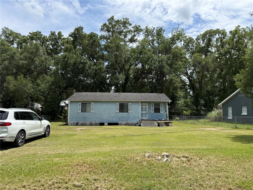 A light blue, single-story house with a lattice foundation sits on a large grassy lot — 4600 SE 136TH LANE, SUMMERFIELD, FL